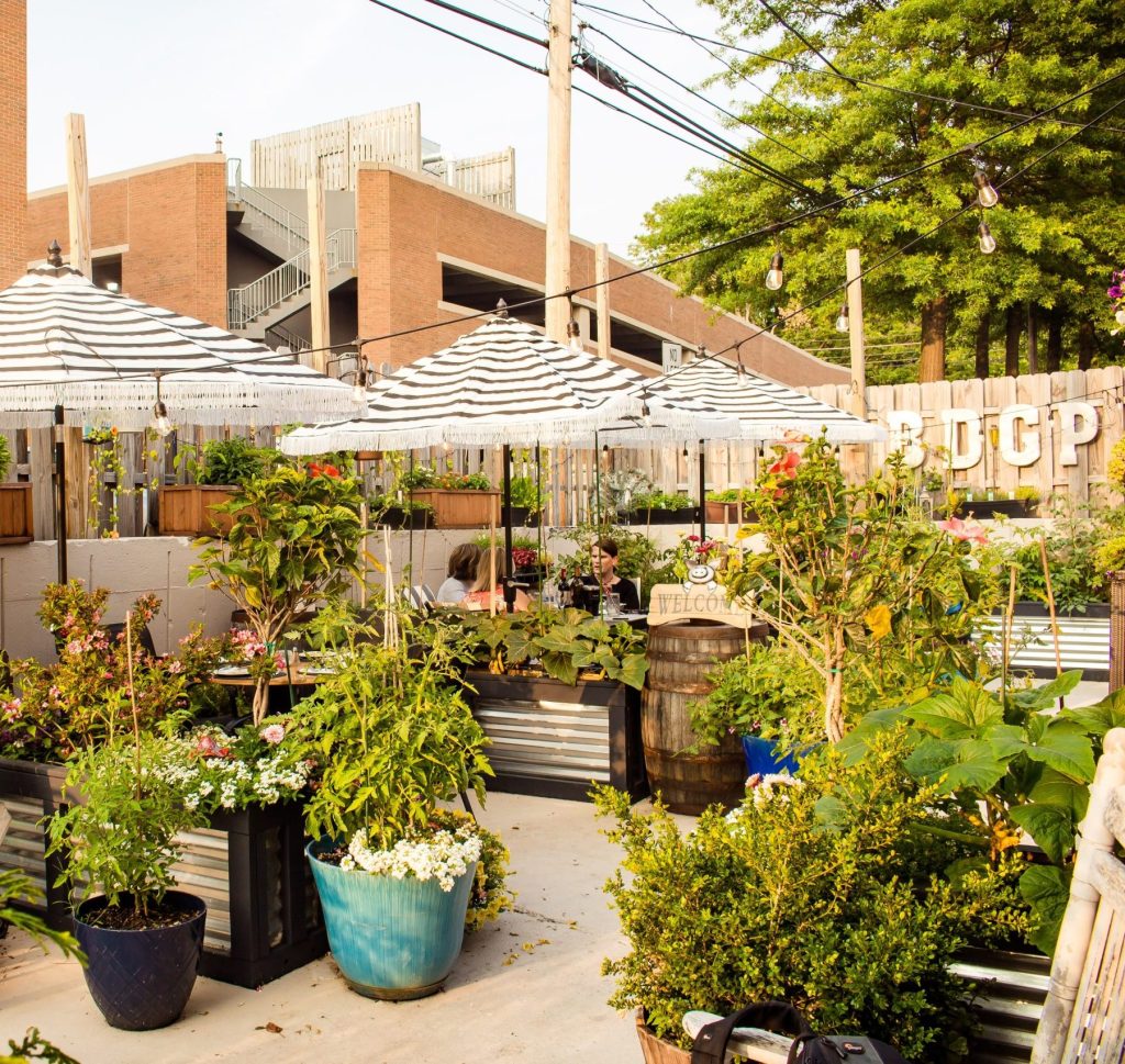 outdoor seating with white and black striped umbrellas, string lights and wooden fences